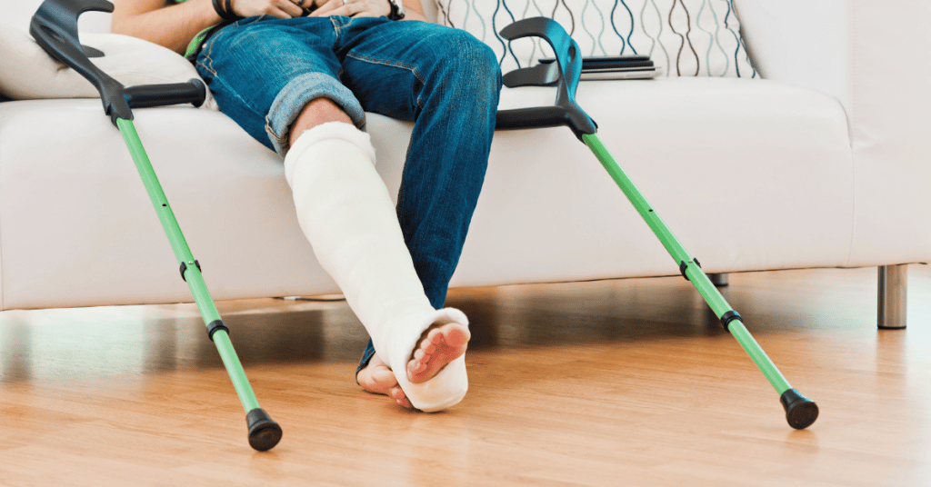Man with broken leg in plaster cast sitting on sofa.